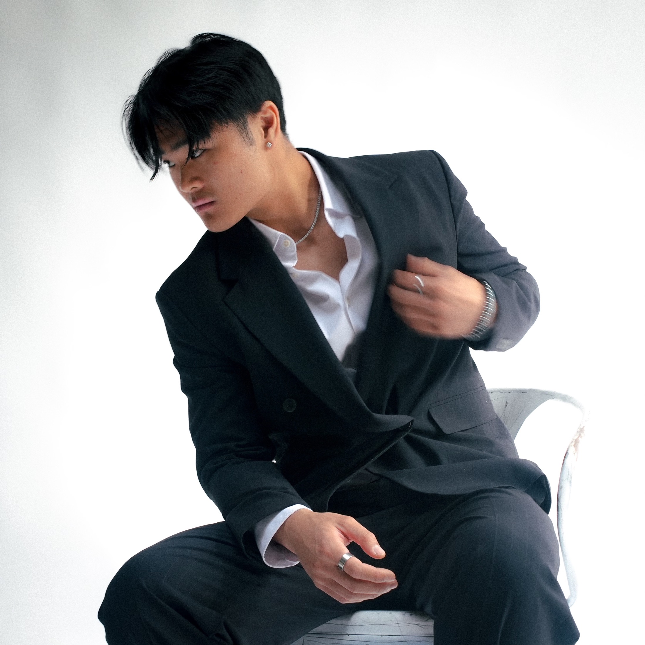DeCC seated in a charcoal suit against a white studio backdrop